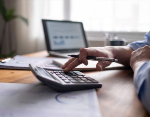 A person is using a calculator and a laptop to prepare their tax return at Candid Books in Melbourne.
