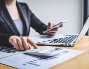 Candid Books' accountant manages tax returns in Melbourne with precision, utilising a calculator, smartphone, and laptop to ensure accurate financial results.